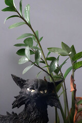 Mysterious funny Black Cat Figurine Amidst Lush Green Foliage