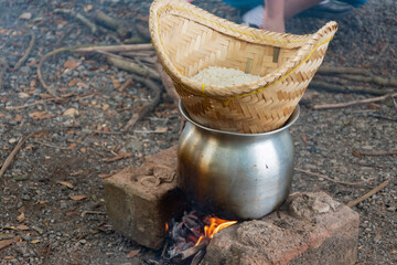 The steaming of glutinous rice over a wood-fired stove by Junior Red Cross students during an outdoor camp.