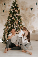 New Year, family, mom and dad with a child hugging each other near the Christmas tree, celebrating the holiday, waiting for the holiday, family New Year photo