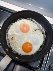 Two fried eggs on a frying pan.
