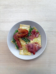 A plate of ravioli with asparagus and prosciutto.