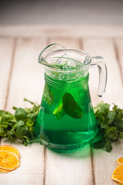 Refreshing green tarragon beverage served chilled with fresh mint leaves and ice cubes in pitcher