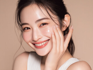 Fototapeta premium 笑顔できらめく綺麗な肌に美容クリームを塗る日本人女性美人モデルの接写写真。スキンケア、コスメ、ビューティーケア広告用