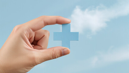 Blue plus sign held between fingers against a soft blue background, symbolizing healthcare and medicine.