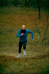 Athlete charging up hill with powerful stride and concentrated drive. Concept of stamina work, force training, outdoor cardio, athletic form, high-effort movement.