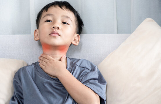 Asian boy suffering from a sore throat and lymphadenitis, holding his neck with pain  discomfort throat and irritation and swollen lymph nodes, 