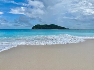 tropical beach scene at Salura Island, East Nusa Tenggara, Indonesia. clear turquoise water, gentle waves washing up on the soft sandy shore.