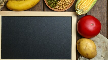 Blank blackboard surrounded by fresh fruits and vegetables on wood