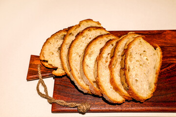 Golden, crunchy bread slices rest on a dark wooden board, highlighting their hearty texture and artisan charm. The scene evokes the warmth of homemade baking and the quiet joy of fresh, natural food.