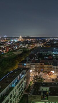 Aerial panorama of Laeken timelapse at night, Brussels Capital Region, Belgium, showcasing cityscape with railway tracks and trains arriving and departing. Historic charm and urban development