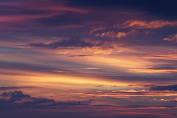Obraz premium Dramatic Sunset Sky - Swirling Clouds Painted with Vibrant Orange and Purple Hues.