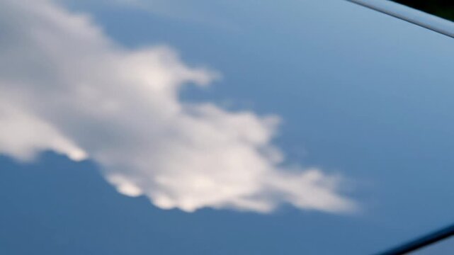 A serene and abstract reflection of a single white cloud drifting across a deep blue sky, mirrored on a glossy surface creating a tranquil and dreamy perspective