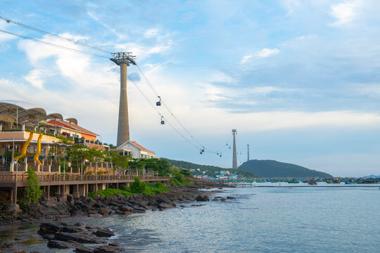 Coast, cable cars, sea, shoreline, fishing boats, harbor, houses, pier, rocky coast, sky, clouds, waterfront, tourism, transport, ocean, seaside, village, hills, towers, landscape
