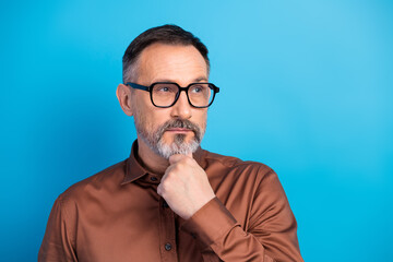 Thoughtful mature businessman in a brown shirt contemplates important ideas while posing for a...