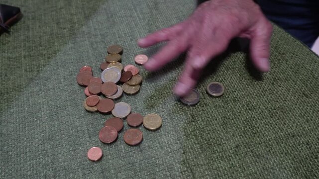 Elderly man counting and sorting euro coins on a table