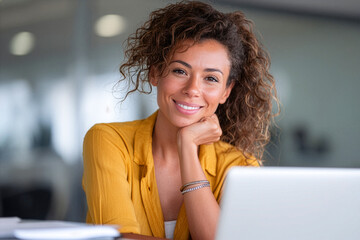 Businesswoman smiling while working on her laptop in a modern office.
