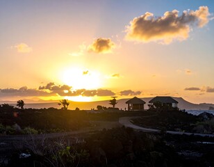 A vibrant sunset over tropical islands, two structures stand on the dark lava-formed landscape