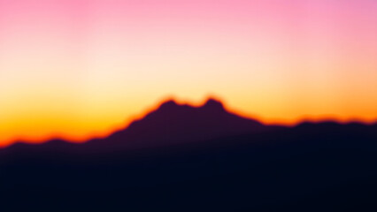 Abstract mountain silhouette at colorful sunset or sunrise blur.