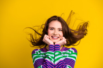 Young woman with striped sweater smiles against a bright yellow background in a casual stylish fashion shoot