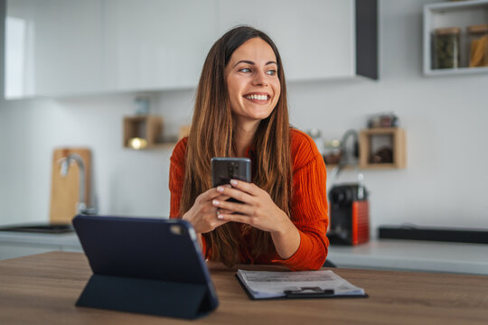 Happy woman using smart phone working from home office