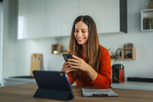Happy woman using smart phone working from home office