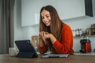 Woman smiling having video call on tablet from home