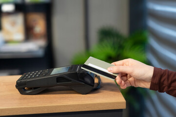 Pay by credit card payment card reader. Close up woman hand using pos cashless wallet NFC technology to pay order on bank terminal. Wireless Contactless payment in store shop cafe or market. Close-up