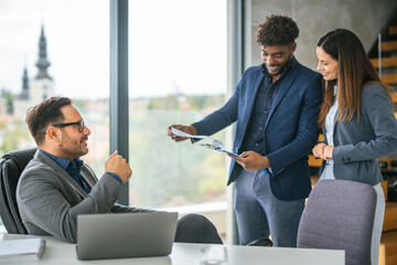 Business colleagues reviewing documents and discussing project in office