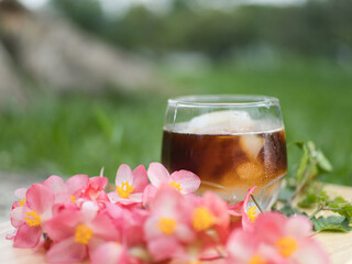 Making iced Americano coffee with fresh palm fruit on a wooden floor surrounded by flowers, relaxing in the park.