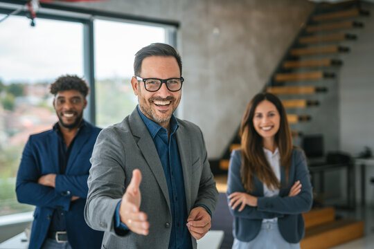 Business leader extending handshake welcoming diverse professional team