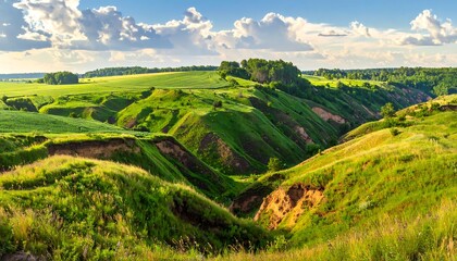 Rolling green hills and a deep valley under a blue sky with fluffy white clouds, filled with light