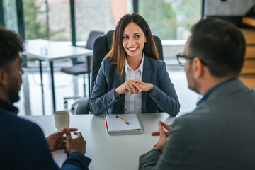 Businesswoman discussing details with diverse clients during meeting