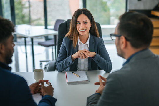 Businesswoman discussing details with diverse clients during meeting