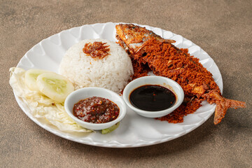 Indonesian fried mackerel or ikan kembung served with crispy kremes topping on a plate.