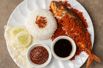 Indonesian fried mackerel or ikan kembung served with crispy kremes topping on a plate.