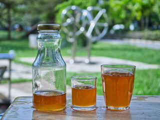 Wild honey in bottles and clear glasses on a wet wooden background