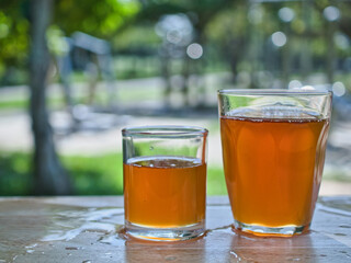 Wild honey in bottles and clear glasses on a wet wooden background