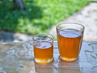Wild honey in bottles and clear glasses on a wet wooden background