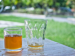 Wild honey in bottles and clear glasses on a wet wooden background