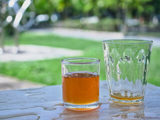 Wild honey in bottles and clear glasses on a wet wooden background