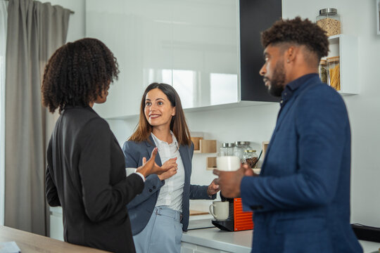 Diverse colleagues discussing business during a coffee break in office kitchen