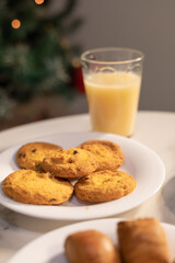 Close-up of assorted cookies and colorful meringues served on plates with a glass of juice on a table.