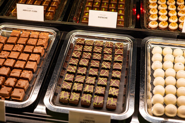 Variety of handcrafted truffles and pralines in a window shop display. Close up, no people