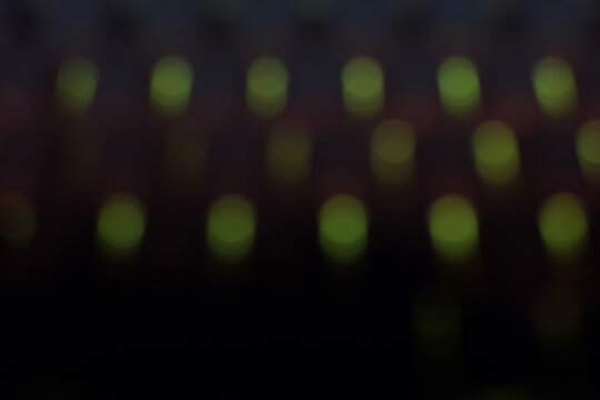 Abstract out-of-focus background showing a grid of glowing green bokeh dots against a deep black setting. The blurred LED lights create a digital, matrix-like pattern evoking technology, code, and cyb
