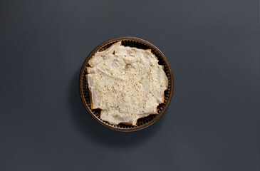 A round dessert features a thick layer of creamy frosting, topped with a sprinkle of black pepper, resting on a dark surface. Perfect for a festive occasion or family gathering.