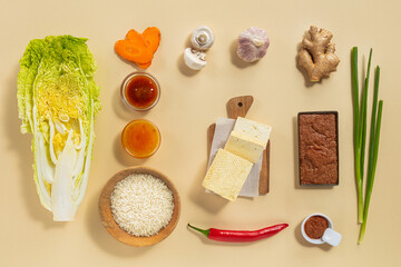 Fresh vegetables, sauces, spices, and rice are neatly arranged on a light surface, showcasing ingredients for a flavorful Asian meal. This colorful display highlights cooking essentials.