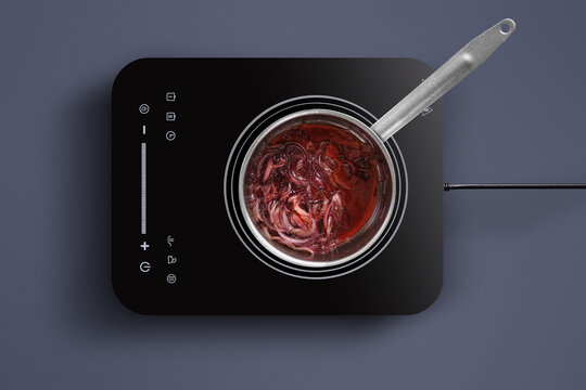 A pot filled with boiling beetroot on a sleek induction cooktop. The vivid red color of the beetroot contrasts with the dark surface, creating an inviting cooking scene in a contemporary kitchen.