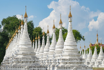 A view of the white stupas of the Sandarmuni Pagoda Buddhist temple on a sunny day. Mandalay, Myanmar