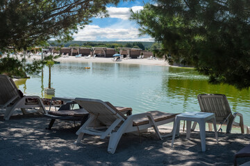 White deck chairs by the lake in the shade between coniferous trees
