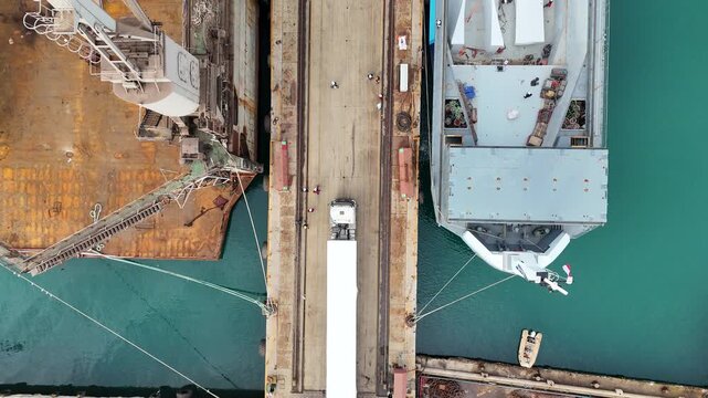 
Footage showing the entrance of a ship inside a marine shipyard, highlighting industrial structures, metal frameworks, and the scale of maritime engineering. The scene represents shipbuilding, mainte